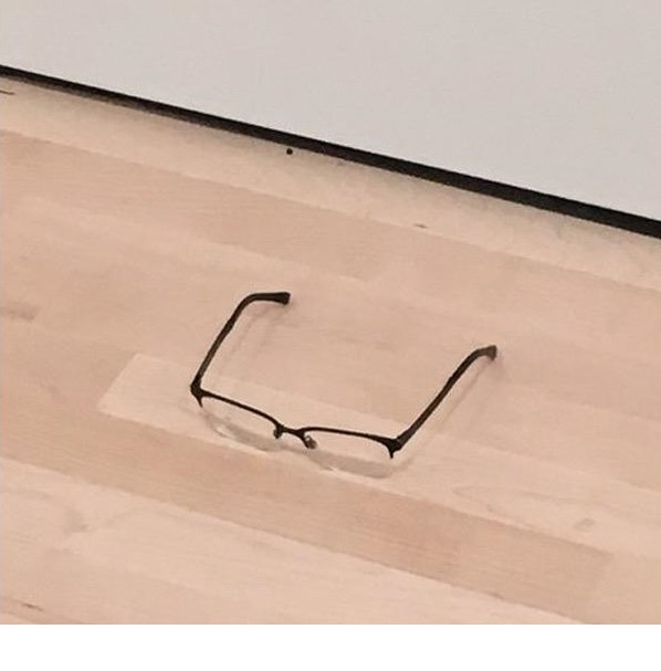 소년이 안경을 미술관 전시회 바닥에 놓았다.